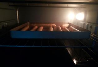 从侧面卷起来，收口，放不粘烤盘烤箱开启发酵键，上下火35度，最下面的烤盘放一点热水，保持湿度，放面包棒再次发酵变大