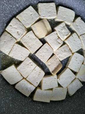 不粘锅内放入少许的食用油，小火加热放入豆腐块