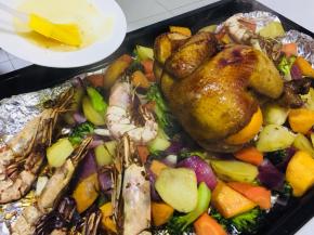 然后铺在烤盘上，取出烤好的鸡去掉锡纸放在蔬菜上，再倒入准备好的水果块。然后四周均匀铺满腌制好的大虾。送入预热后的烤箱180度，再烤30-40分钟