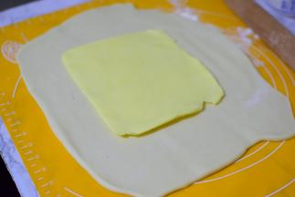 把面团擀成方形，把冰箱冷藏的黄油片，放在中间