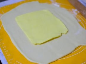 把面团擀成方形，把冰箱冷藏的黄油片，放在中间