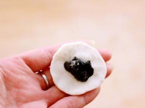 取白色面团按成圆饼后包入馅料