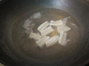 在煮面条的锅中将鱿鱼焯水，鱿鱼卷起来立马捞出。