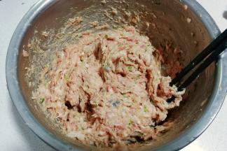 将拌均匀的馅料取一半出来放入另外一个盆中，顺着一个方向搅打上劲；