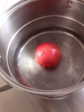 一个西红柿洗净，表面切十字刀，放入开水锅中烫一会