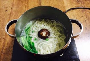 然后再次开火煮至沸腾，把豌豆、鲜香菇、小油菜依次放入锅里煮开。