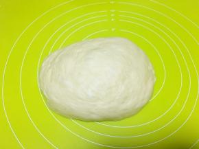 将发酵好的面团放在揉面垫偏黄按压排气