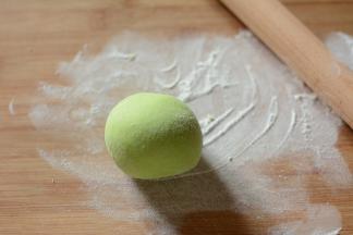 将面团在反复揉搓一遍，然后在面团撒上一些干粉，将面团压扁。