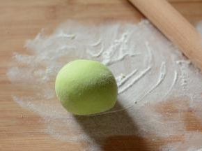 将面团在反复揉搓一遍，然后在面团撒上一些干粉，将面团压扁。