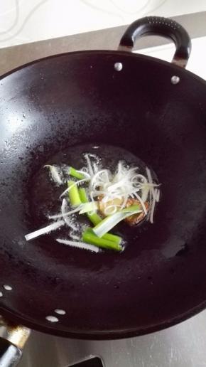 锅里放入比平时炒菜多一倍的油，烧至温热时关火，放入葱姜先靠出香味；