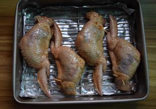 用牙签将鸡翅口别上，把鸡翅刷一遍腌制的酱汁，放在烤网上，腌制10分钟