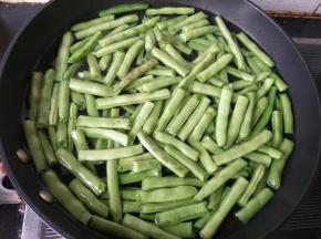 水烧开后倒入四季豆，不盖锅盖。