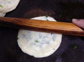 用手捏饺子皮的边缘，以防油和葱会漏出。然后用擀面杖从中间向外面按压