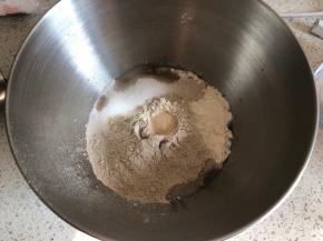 厨师机面盆内先倒入清水，再倒入高筋面粉和黑麦粉，盐和糖对角线放置，面粉中间挖一小坑放入活性干酵母