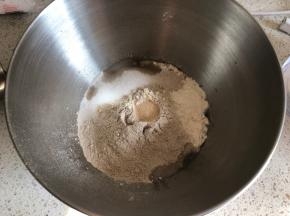 厨师机面盆内先倒入清水，再倒入高筋面粉和黑麦粉，盐和糖对角线放置，面粉中间挖一小坑放入活性干酵母