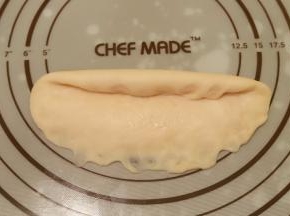 取一小份面团，擀成牛舌状，翻面，从上往下卷，下面用手指轻压，收口捏紧