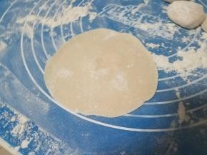 用擀面杖把小面团擀成圆形的面片。