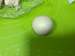 将面团取出揉圆，搓成长条，切割为约57g一个的小面团9个，将小面团揉圆