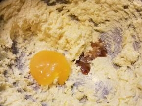 接着把1个蛋黄和1g香草精也加进去，继续用打蛋器最低那一档把蛋黄混匀进去，必须确保混匀了，期间用刮刀挂一下碗边，它和盐都是用来调味的，这样黄油曲奇味道才不会只有甜味那么单调，有一丝丝的咸和香草味。
