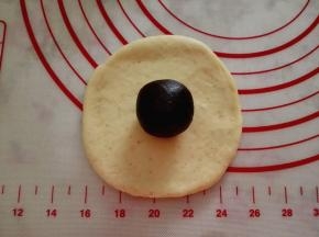 4.	取一个面团擀圆，中间包入适量豆沙馅