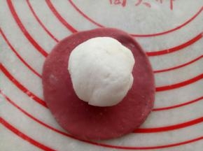 取一块红色面团擀成圆形包上一块白色面团。