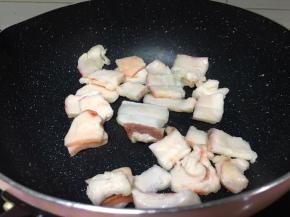 锅里放肥肉块中火翻炒，炸出油