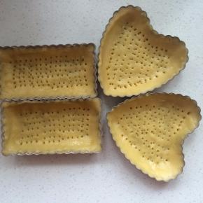 取出面团，取出适量装入派盘中，用手从中间向四边推，推满整个模具，底部用叉扎满小洞