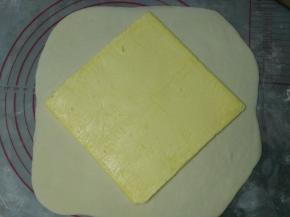 取出冰箱里的面片，擀成大约22CM大小的正方形，放入黄油，包住捏紧收口