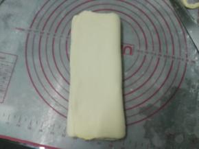 用擀面杖，擀成长方形的面片，用力要均匀，把两段没有黄油的地方切除，折成三折，静置15分钟，室温高的时候要放入冰箱冷藏；