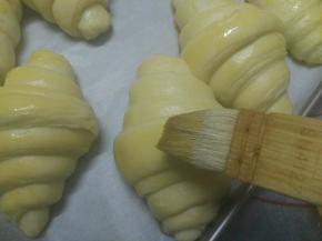 发酵到可颂面团摇摇欲坠即可，发酵好的可颂面团拿出来刷蛋液，注意蛋液要用水稀释，不然上色会很深，此时烤箱预热210度10分钟