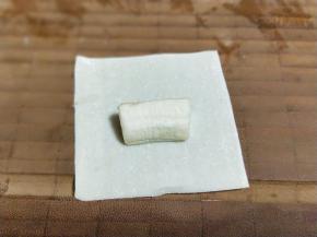 取一张小馄饨皮，放入切好的香蕉块儿。将馄饨皮的一端对折。再将另一端对折，如图