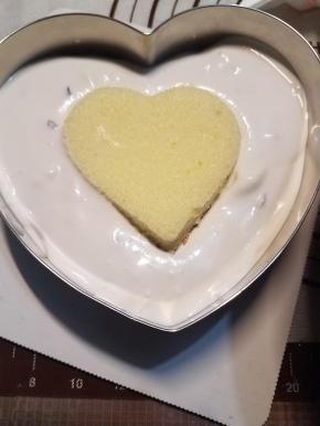 在慕斯圈内放入蛋糕底，然后倒入大部分慕斯糊，再压一块小一点的蛋糕片放入慕斯糊内，最后把剩余的慕斯糊倒入，涂抹均匀