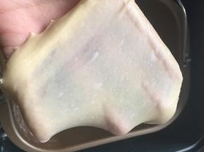 揉好的面团取出一小团，拉着面团两段轻往两边拉出易破薄膜，洞周边有带齿边