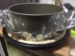 取一张锡纸稍稍揉搓成稍柔软状态，展开平铺在面皮上，取一个戚风蛋糕模具（或者重物）放置在锡纸上