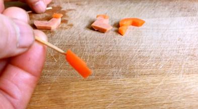 将火腿肠切成靴子样，红萝卜切成树叉样，用牙签插上