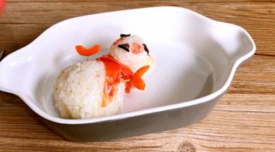 用番茄皮做围巾，将红萝卜树叉插两边，当圣诞老人的双手，用紫菜剪成眼睛嘴巴形状，贴在小饭团上做圣诞老人的眼睛和嘴巴，再用番茄沙司做圣诞老人的脸
