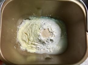 把食材中除黄油、鸡蛋液和糖霜之外的材料放入面包桶，先放水，在对角处放入盐和糖，再放入面粉和奶粉，最后再面粉上掏一个洞倒入酵母。