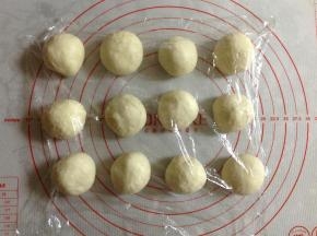 然后把面团取出，平均分成12份，盖上保鲜膜松弛10分钟。