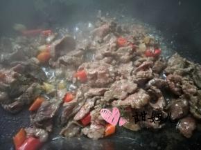 下牛肉快速翻炒至发白，加入红色小米椒继续翻炒