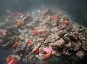 下牛肉快速翻炒至发白，加入红色小米椒继续翻炒