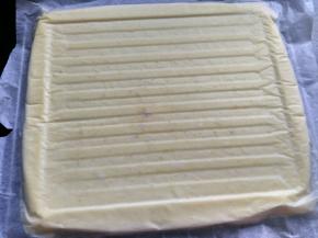 将蛋糕将烤盘倒扣，趁热取下油纸。