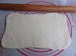 发酵好的面团取出排气，揉啊揉，大概揉8分钟，揉至面团光滑，切面没大气孔即可。如果面团有点粘手，可以在案板上洒点面粉。将面团擀成长方形，四个角擀开，翻面再擀擀，尽量弄成长方形吧