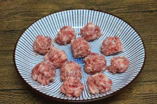 抓起肉糜，肉丸从虎口处挤出，搓好的丸子放在一旁待用