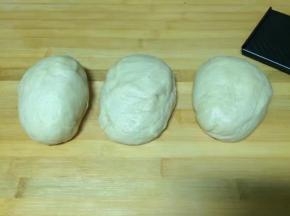 发酵好的面团，直接在面包机中启动揉面程序，面团排气8分钟，取出后分出一半面团做小面包，另一半做吐司，先把这一半面团分成三个大剂子