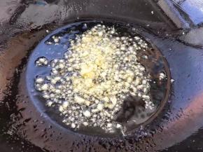 把刚才炸豆腐用的油倒出来一部分，留一点放锅中，大蒜剁碎放入锅中炒出香味。

