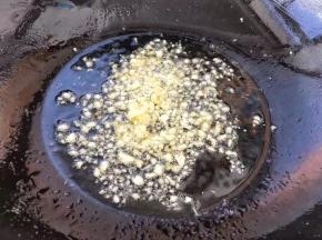 把刚才炸豆腐用的油倒出来一部分，留一点放锅中，大蒜剁碎放入锅中炒出香味。
