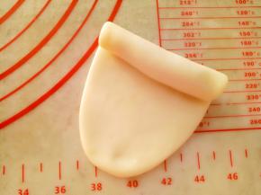 把包好的酥皮用擀面杖擀成牛舌形（长度10CM左右）卷起来。
