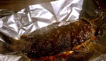 将烤盘铺上锡纸，再将腌制好的鲫鱼放在锡纸上，撒上花椒粉、孜然粉，淋上香辣油