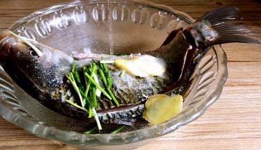 鲫鱼放入碗内，加入部分葱段，姜片、盐和料酒，抹匀后腌制半小时