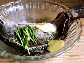鲫鱼放入碗内，加入部分葱段，姜片、盐和料酒，抹匀后腌制半小时
